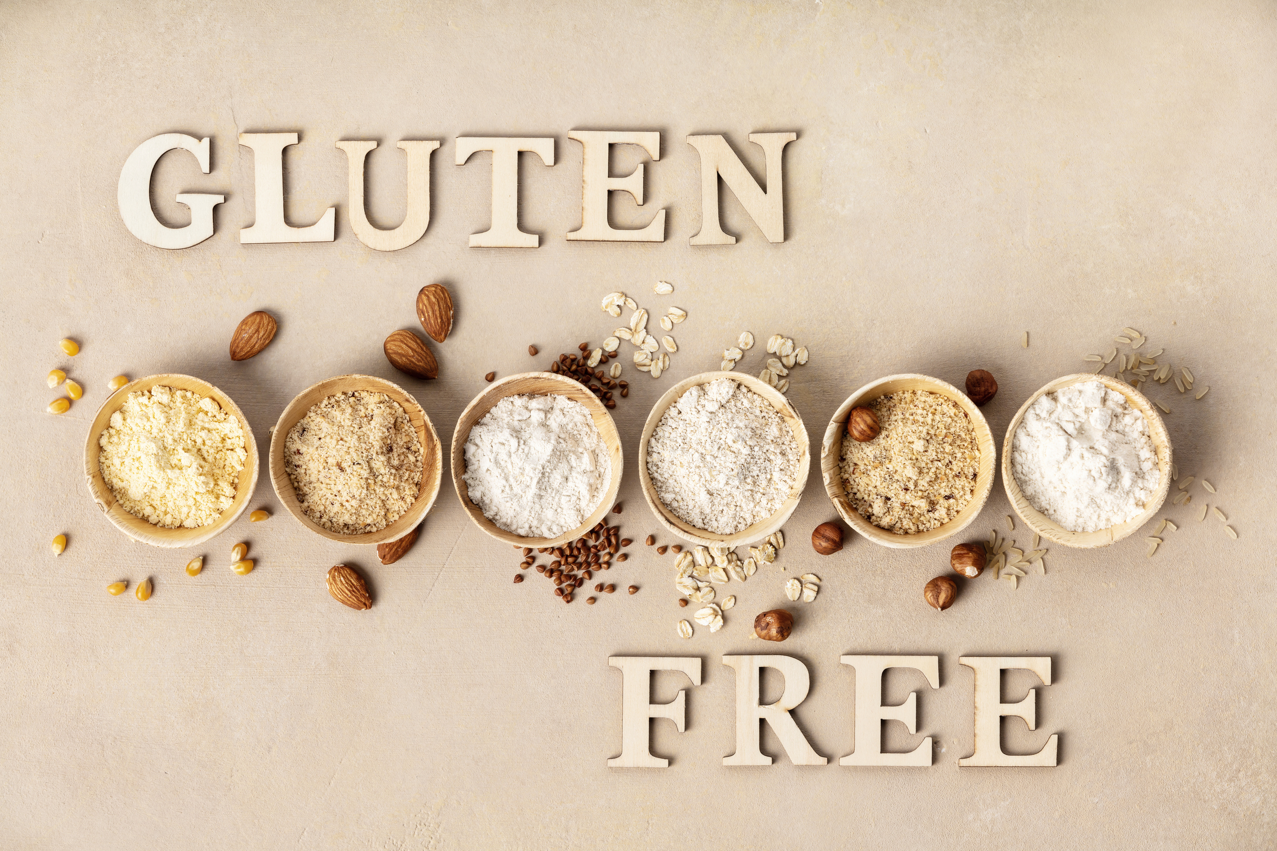 Various gluten free flour almond flour, oatmeal flour, buckwheat flour, rice flour, corn flour and gluten free lettering made of wooden letters, top view, flat lay