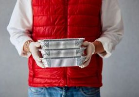 delivery person holding ready made meal boxes in hand